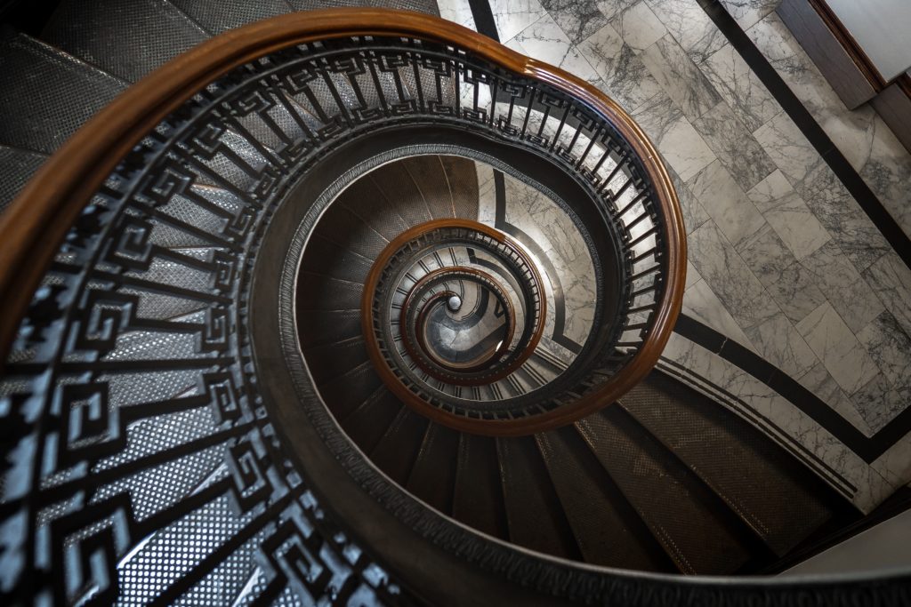 A spiral staircase, photographed from the top. It is a confusing image to understand what is going on, as the concentric circle gets smaller and smaller as it goes down.