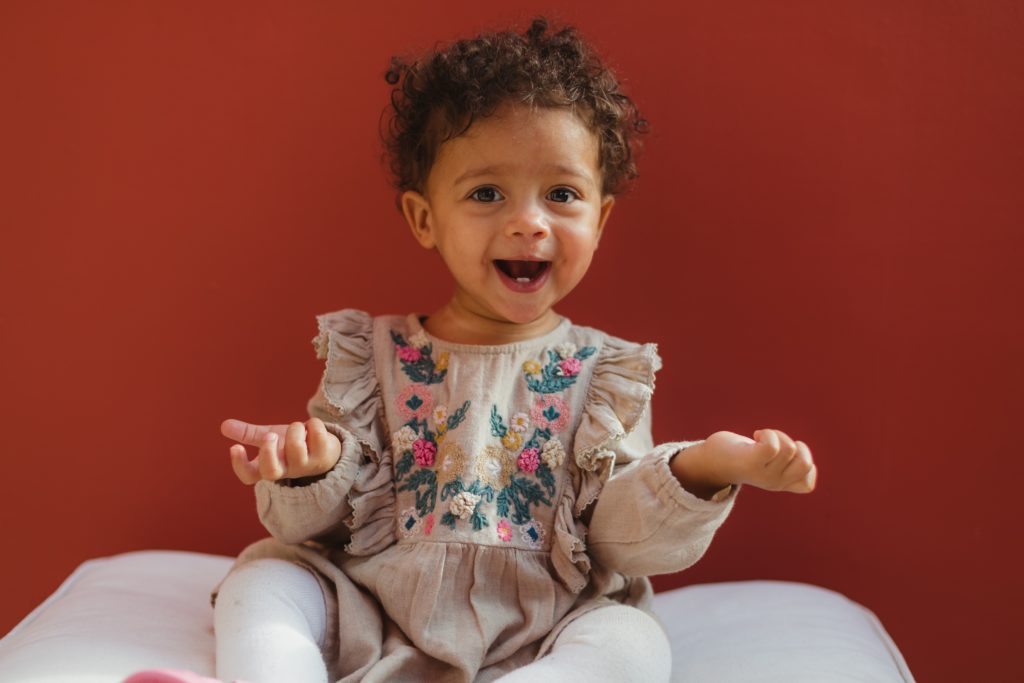 Cute girl, sitting in a meditation pose, with a grin, looking like she is quite wise and lighthearted.